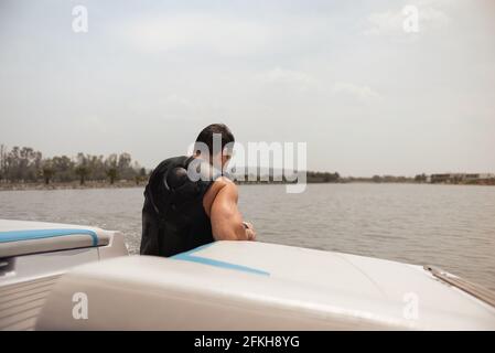 Homme hispanique assis, calme, dans un bateau sur le lac à midi Banque D'Images