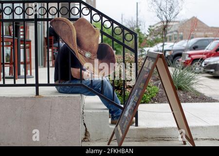 Roanoke, Texas, États-Unis. 1er mai 2021. 5/1/21 Roanoke, Texas - UN homme s'assied sur les marches à la 5e Roanoke Roundup annuelle. Il s'agit de l'une des premières foires publiques qui ont eu lieu depuis que le Texas a ouvert 100 % depuis que la pandémie COVID-19 a frappé l'État. Crédit : Chris Rusanowsky/ZUMA Wire/Alay Live News Banque D'Images