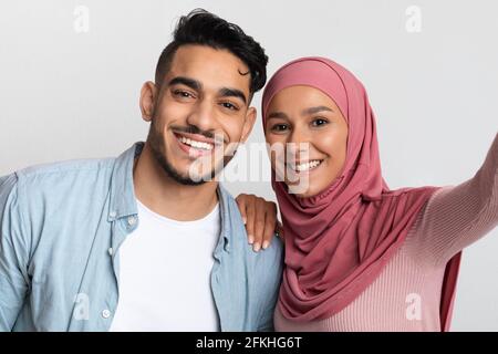 Joyeux jeune homme arabe et femme musulmane dans la prise de hijab Selfie ensemble Banque D'Images