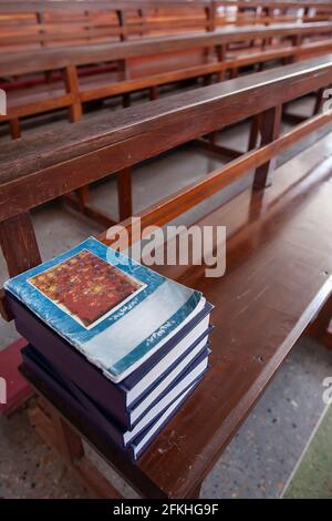 Livre de prière catholique thaï sur les rangées de bancs d'église en bois, lumière douce de beaming brille à l'intérieur d'une église. Ancienne église en Thaïlande. Banque D'Images