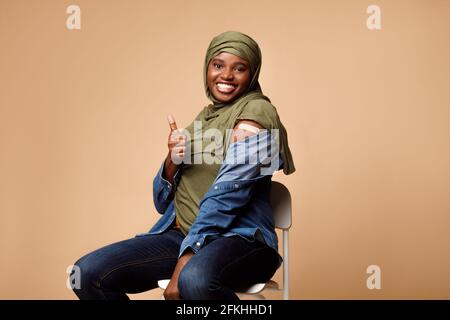 Black Muslim Lady vaccinée contre Covid-19 montrant comme geste, Studio Banque D'Images