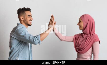 Concept de travail d'équipe. Joyeux couple musulman joyeux donnant le Haut cinq l'un à l'autre Banque D'Images