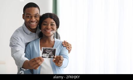 Couple afro-américain attrayant posant avec un bébé sonogramme Banque D'Images