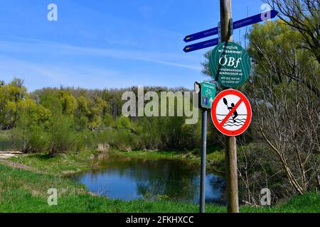 Haslau, Autriche - 24 avril 2021 : paysage avec lac oxbow et panneau indiquant la distance et un panneau sur la piste cyclable ainsi qu'un iti interdit Banque D'Images