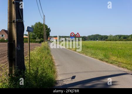 Rue rurale avec câbles électriques aériens à Grobbendonk sur un jour de printemps ensoleillé Banque D'Images