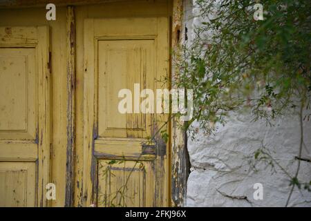 Ancienne maison rurale porte en bois décolorée sur un mur de pierre patiné à Leonidio, Arcadia Péloponnèse, Grèce. Banque D'Images