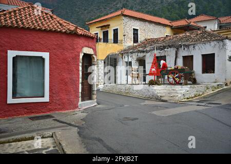 Maisons rurales traditionnelles et le Père Noël en calèche avec des cadeaux de Noël et des décorations festives à Leonidio Arcadia, Péloponnèse, Grèce. Banque D'Images