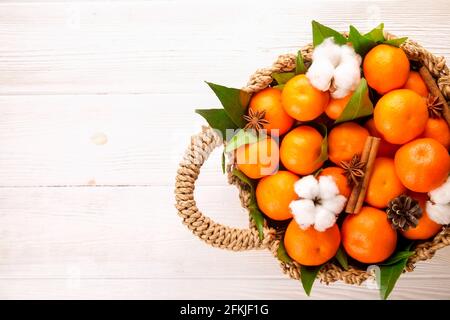 Panier rempli d'oranges de clémentine fraîches entières juteuses avec feuilles sur table texturée en bois blanc. Mandarines saines, aliments végétaliens/végétaliens, vitami Banque D'Images