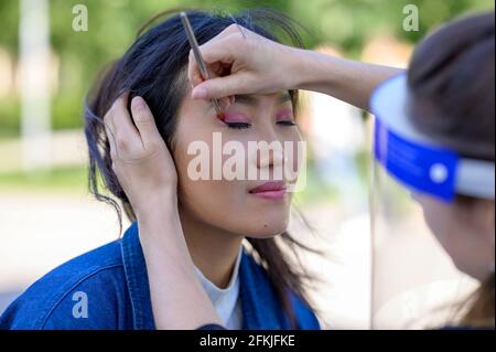 Une jolie mongole est composée dans un parc par un maquilleur pour une séance photo. Banque D'Images