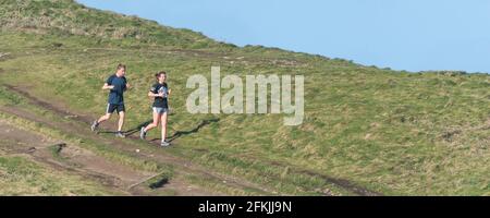 Image panoramique d'un coureur mâle et d'une femelle sur un sentier de Towan Head à Newquay, en Cornouailles. Banque D'Images
