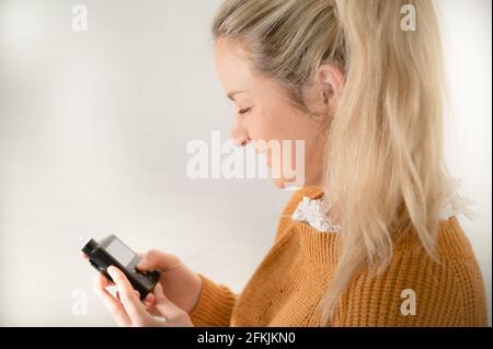 Belle femme blonde tenant sa pompe à insuline - traitant le diabète avec la technologie Banque D'Images