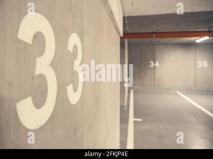 Espaces de garage pour voitures souterraines résidentielles entièrement en béton. Numéros d'espace peints sur les murs du bâtiment. Banque D'Images