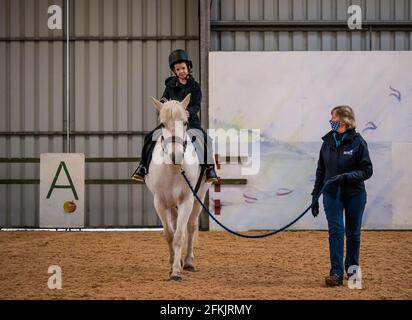 Garçon à cheval, équitation pour handicapés à Muirfield Riding Therapy, East Lothian, Écosse, Royaume-Uni Banque D'Images