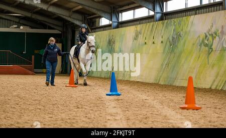 Garçon à cheval blanc apprenant contrôle de rein, équitation pour handicapés à Muirfield Riding Therapy, East Lothian, Écosse, Royaume-Uni Banque D'Images