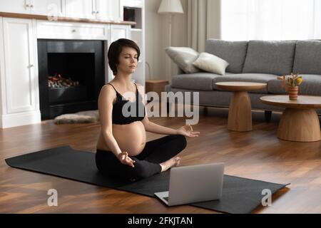 La jeune femme enceinte a un cours de yoga en ligne Banque D'Images