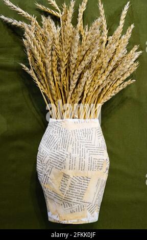 Un bouquet de pointes de blé dans un vase en papier. Vie encore faite à la main. Banque D'Images