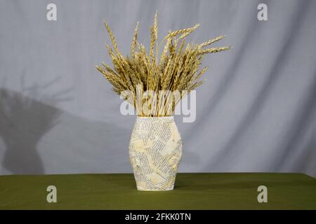 Un bouquet de pointes de blé dans un vase en papier. Vie encore faite à la main. Banque D'Images