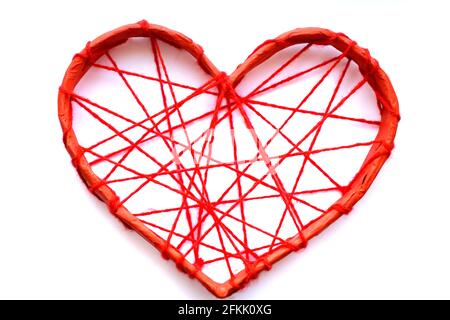 Un coeur en papier attaché avec des fils rouges. Cœur sur fond blanc. Banque D'Images