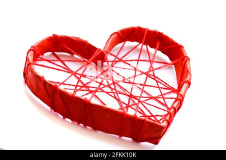 Un coeur en papier attaché avec des fils rouges. Cœur sur fond blanc. Banque D'Images