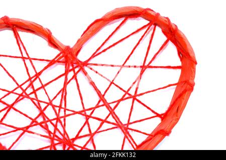 Un coeur en papier attaché avec des fils rouges. Cœur sur fond blanc. Banque D'Images