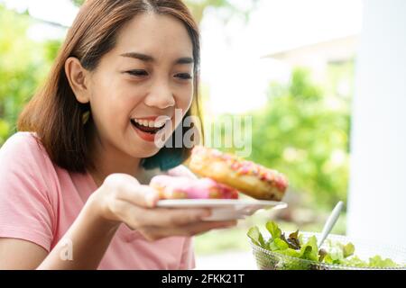 La belle femme asiatique en bonne santé d'âge moyen est heureuse de manger des beignets parce qu'ils n'ont pas mangé pendant longtemps parce qu'elle espère la santé. Concept o Banque D'Images