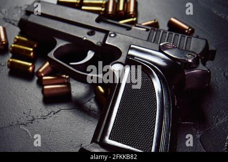 Pistolet noir avec cartouches sur table. Armes sur fond concret. Arme pour la défense ou l'attaque. Armes à feu automatiques avec balles. Banque D'Images