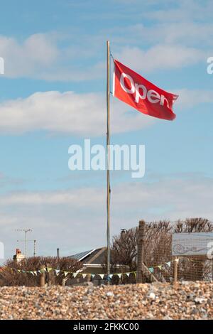 drapeau « ouvert » soufflant dans le vent. Une petite entreprise locale fait savoir à son client qu'il est de nouveau ouvert à l'entreprise après le verrouillage de Covid-19 2021 Banque D'Images