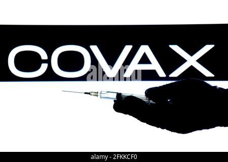 Madrid, Espagne - 2 mai 2021 : seringue à main avec vaccin Covid-19 et logo Covax sur fond blanc. Banque D'Images