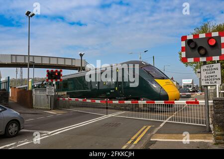 Pencoed, près de Bridgend, pays de Galles - avril 2021 : les feux d'avertissement rouges clignotent en train à grande vitesse passant par le passage à niveau du village Banque D'Images