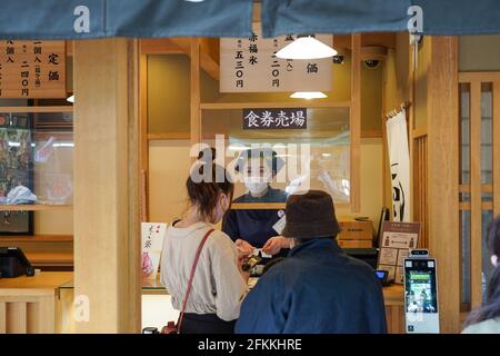 ISE, Japon. 1er mai 2021. Un personnel communique avec un client par l'intermédiaire d'un écran en plastique à la caisse du magasin de thé pendant les fêtes de la semaine d'or. Les leaders de la préfecture du Japon ont exhorté les habitants à éviter les déplacements inutiles, le pays étant confronté à une quatrième vague de pandémie du coronavirus avec moins de trois mois pour se rendre jusqu'aux Jeux olympiques de Tokyo. Crédit : SOPA Images Limited/Alamy Live News Banque D'Images