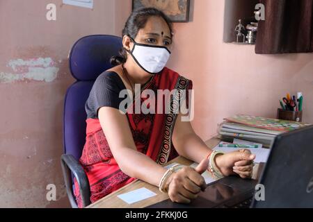 Une femme enseignante indienne dans un masque facial à l'aide d'un ordinateur portable à l'école pendant la pandémie de Covid-19 Banque D'Images