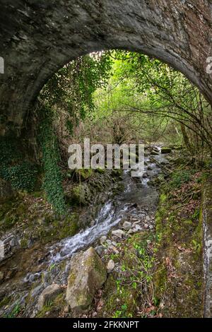 Ancien pont romain caché dans la forêt près de Castiglion Fiorentino, Arezzo, Toscane, Italie. Un beau ruisseau coule sous lui Banque D'Images