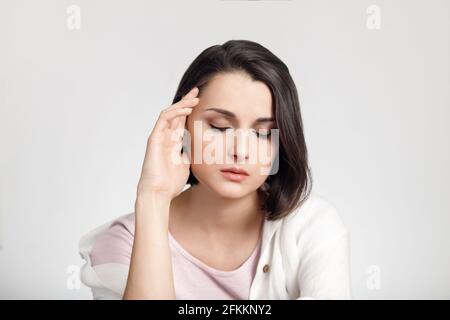 Jeune femme fatiguée avec les yeux fermés tenant la tête. Banque D'Images