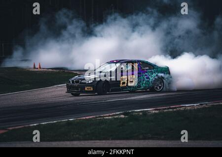 01-05-2021 Riga Lettonie. Flou de la diffusion de l'image dérive de course voiture avec beaucoup de fumée de la combustion des pneus sur la piste de vitesse Banque D'Images