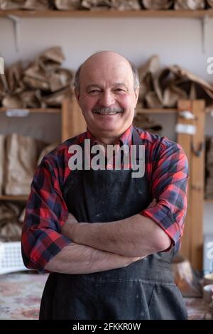 Artisan hispanique senior heureux debout en studio. Banque D'Images