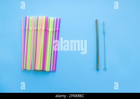 De nombreuses pailles à boire en plastique contre une paille réutilisable à boire en bambou sur un fond bleu. Une vie durable zéro déchet, concept sans plasticité. Réfrigérateur ECO Banque D'Images