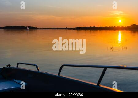 Lac Masurien, coucher de soleil, bateau à moteur sur la rive du lac. Banque D'Images