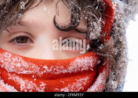 Un gros plan d'un garçon habillé pour l'hiver couvert dans la neige Banque D'Images