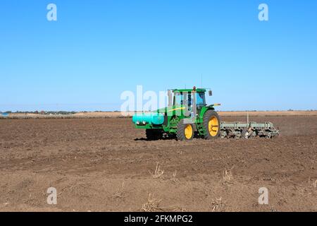 Tracteur John Deere 8120 labourant un champ de coton près de Narrabri, Nouvelle-Galles du Sud, Australie. Un réservoir d'engrais liquide est situé à l'avant du tracteur. Banque D'Images