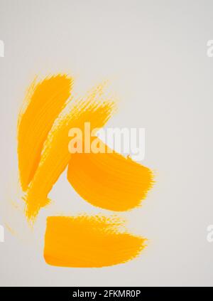 Fait à la main, peint à la main de traits de pinceau acrylique jaunes sur fond blanc. Texture artistique fluide sur toile. Style d'image vertical. Banque D'Images
