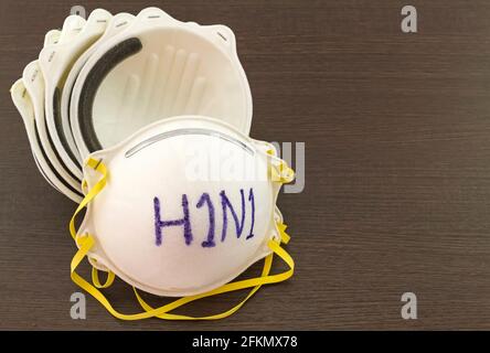 Gros plan de la pile de masques blancs et du mot H1N1 in masque sur fond en bois noir, retouche dans la prévention de la grippe Banque D'Images