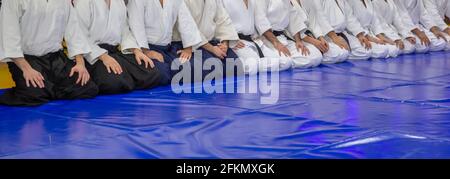 Étudiants en arts martiaux assis sur des tapis bleus dans la salle du dojo. aikido Banque D'Images