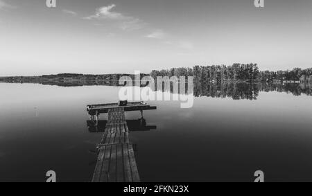 Noir et blanc lumineux paysage rural avec jetée en bois et lac calme pendant la matinée d'été Banque D'Images