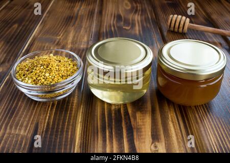 Différentes variétés de miel en petits pots de verre et pollen d'abeille sur fond de bois brun. Gros plan. Banque D'Images