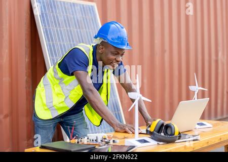 Spécialiste Afro-américain de l'industrie, de l'usine et de l'énergie. Portrait noir homme d'ingénierie tenant le modèle de réservoir de moulin à vent et la cellule solaire sur Banque D'Images