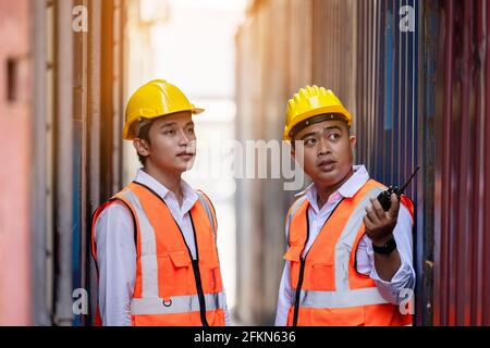 Deux ouvriers d'usine ou ingénieurs qui cherchent et pointent quelque chose conteneurs stockage en entrepôt Banque D'Images