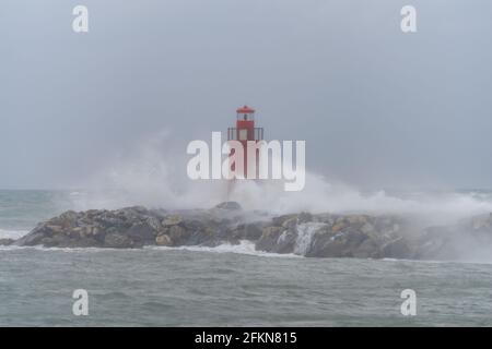 Vagues s'écrasant sur le brise-lames avec le phare dans le port d'Imperia, en Italie Banque D'Images