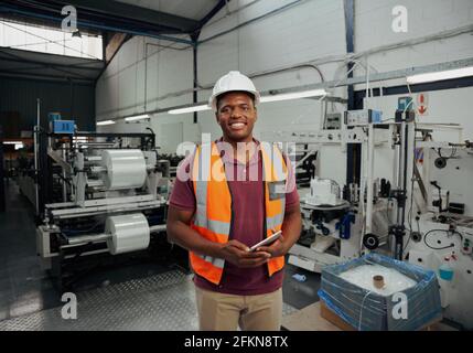 Un bon superviseur africain dans un entrepôt qui tient une tablette numérique main Banque D'Images