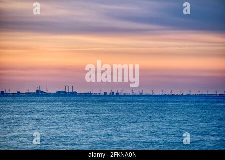 Horizon de Copenhague au coucher du soleil avec des turbines en rotation dans le parc éolien danois. Centrale éolienne de la mer Baltique avec la ligne d'horizon industrielle de la ville Banque D'Images