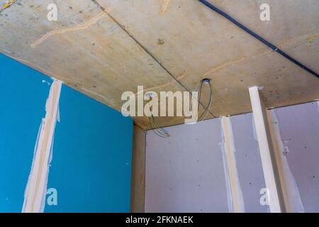 Intérieur d'un nouvel appartement en construction sans finition dans des tons sombres avec trous électriques et câblage pour projecteur de plafond. PH de haute qualité Banque D'Images